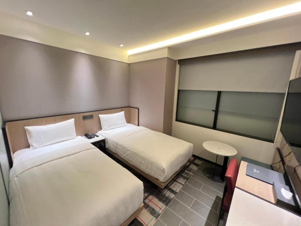 a room with two beds and a table and a mirror at Hotel Midtown Richardson in Taipei