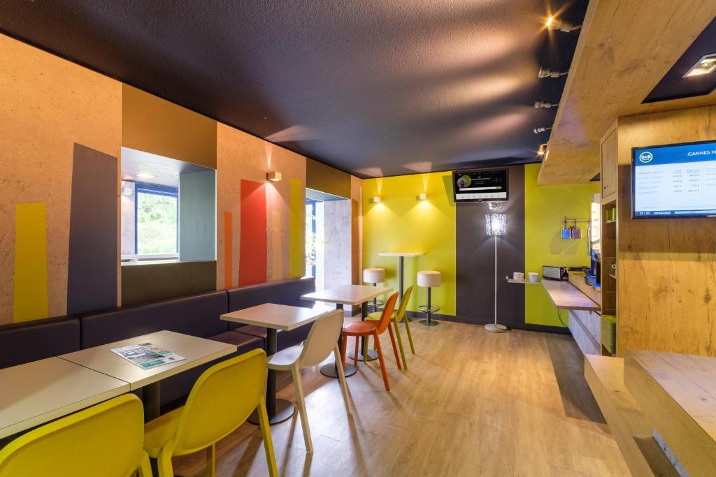 ein Restaurant mit farbenfrohen Wänden, Tischen und Stühlen in der Unterkunft B&B HOTEL Cannes Mouans Sartoux in Mouans-Sartoux