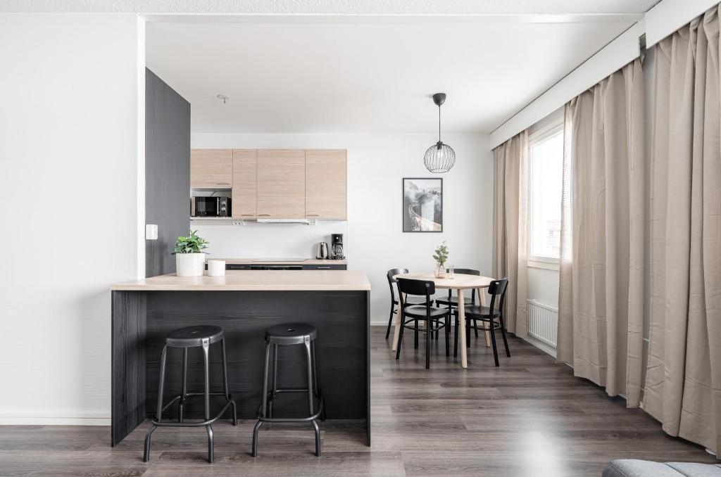 a kitchen with white walls and a black island with bar stools at 2ndhomes Tampere "Otavala" Apartment - Just Renovated - Hosts 8 in Tampere