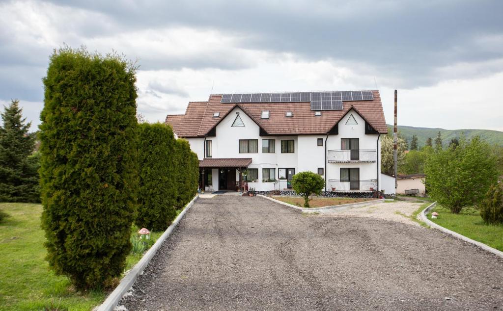 a large white house with solar panels on the roof at Pensiunea Poarta Apusenilor in Moldoveneşti