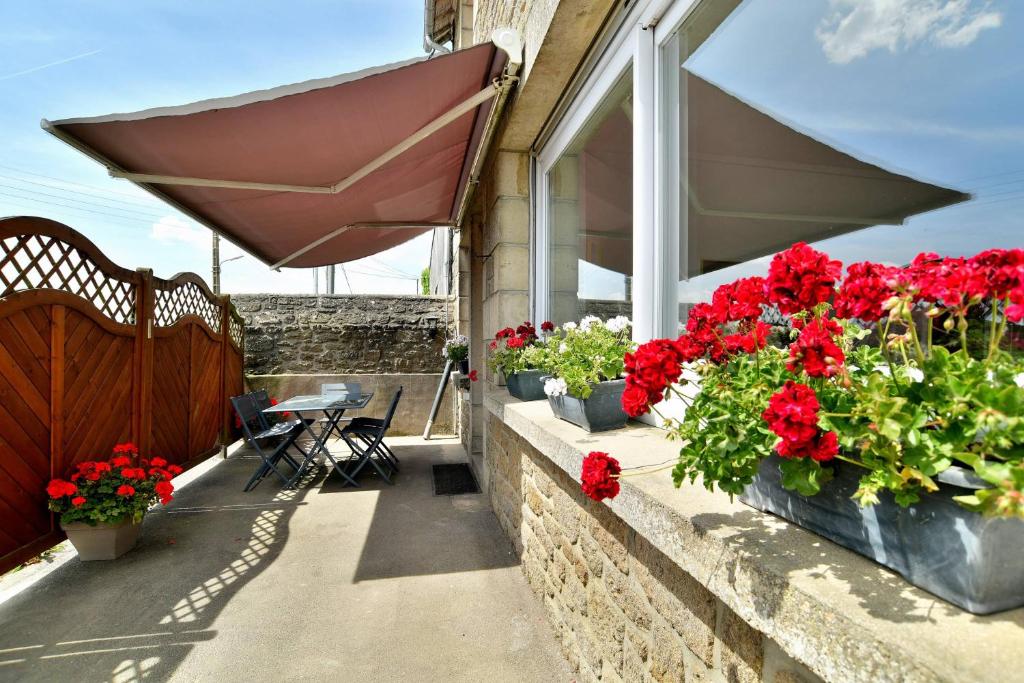 un balcón con flores rojas y una sombrilla en Maison spacieuse à saint coulomb, en Saint-Coulomb