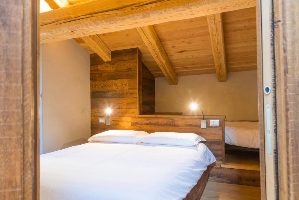 een slaapkamer met een groot wit bed en houten wanden bij LA PLACETTE - Albergo diffuso e Trattoria in Usseaux