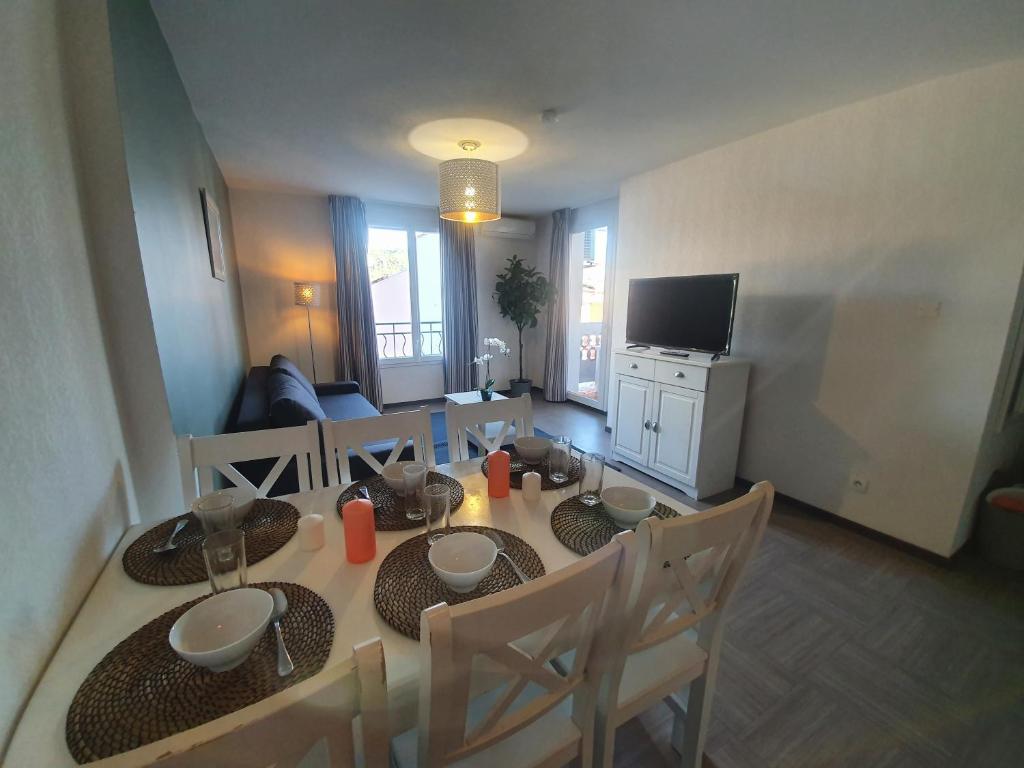 une salle à manger avec une table, des chaises et une télévision dans l'établissement Le Lavandin - T3 Piscine & Climatisation, à Gréoux-les-Bains
