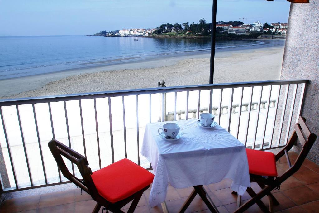 een tafel en stoelen op een balkon met uitzicht op het strand bij Desconectaengalicia Paseo Silgar, 4 dormitorios in Sanxenxo