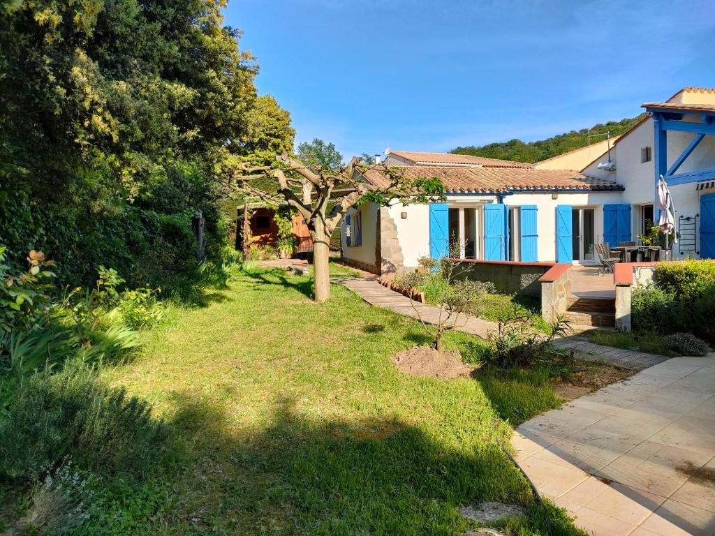ein Haus mit einem Garten mit einem Baum darin in der Unterkunft MAS VALLCROSA Studio calme et confortable avec piscine in Camélas