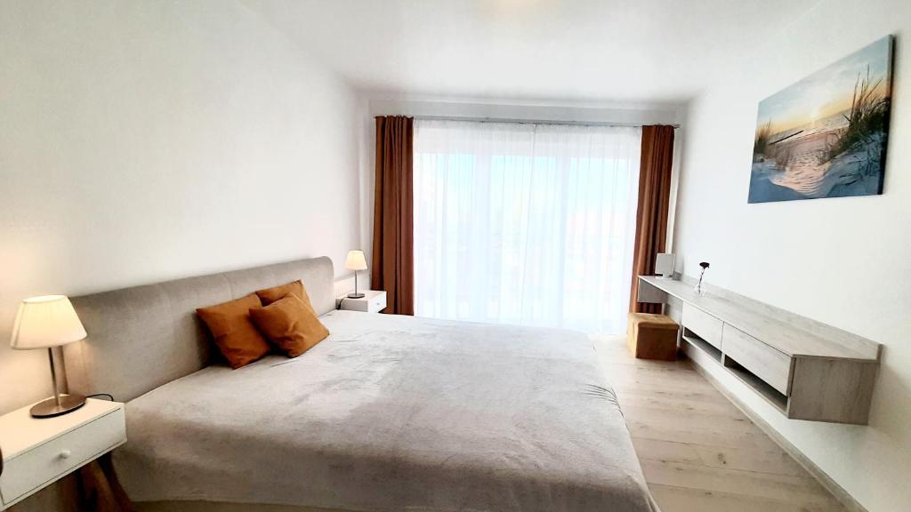 a white bedroom with a large bed and a window at Apartamenty Aleksandry _ Flotylla in Świnoujście