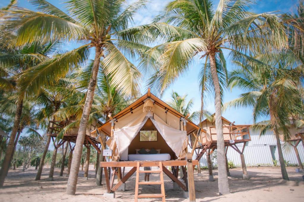 une cabane dans les arbres sur la plage avec des palmiers dans l'établissement Hola Beach - Beach Club & Eco Glamping Resort, à Ke Ga