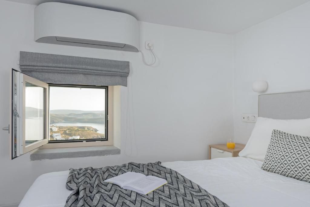 a white bedroom with a bed and a window at Akro Luxury Living in Astypalaia Town