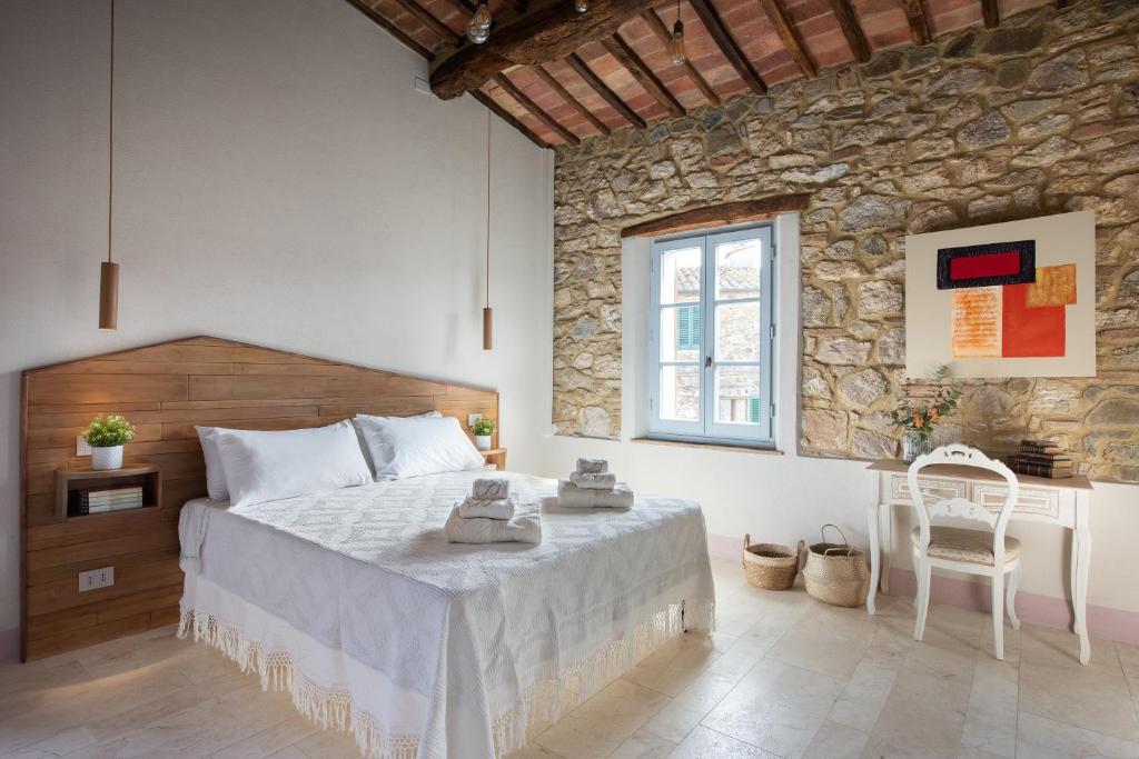 1 dormitorio con 1 cama grande y pared de piedra en La Casetta di Nise, charming private spa, en Castelnuovo dellʼAbate