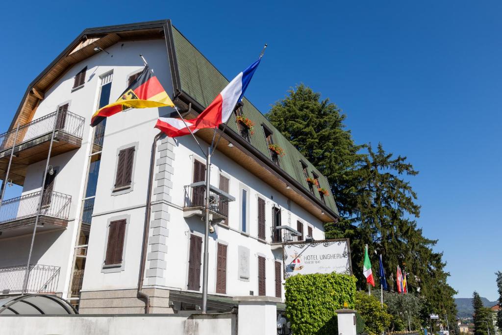 un bâtiment avec des drapeaux sur son côté dans l'établissement Hotel Ungheria Varese 1946, à Varèse