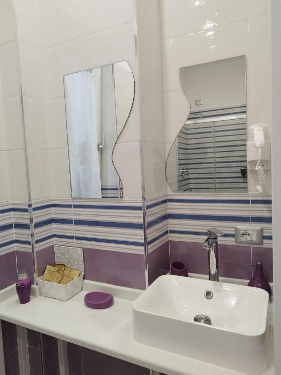 łazienka z białą umywalką i lustrem w obiekcie B&B Molo Partenope w mieście Neapol