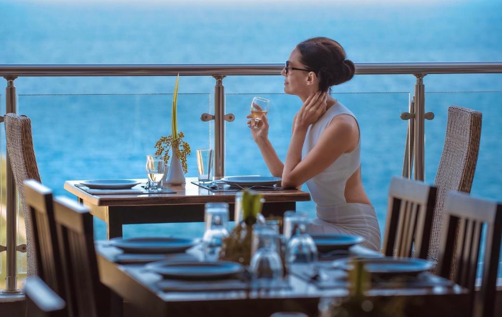 a woman sitting at a table with a glass of wine at Iridescent Clouds Hotel Nha Trang -Mây Ngũ Sắc in Nha Trang