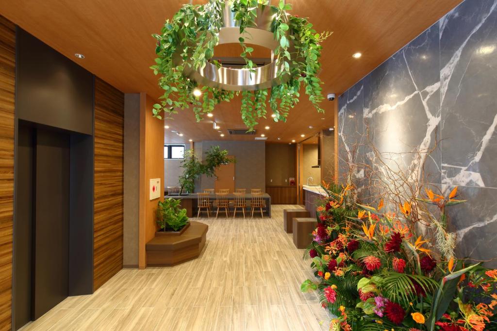 a lobby with flowers and a chandelier at LUXCARE HOTEL in Osaka