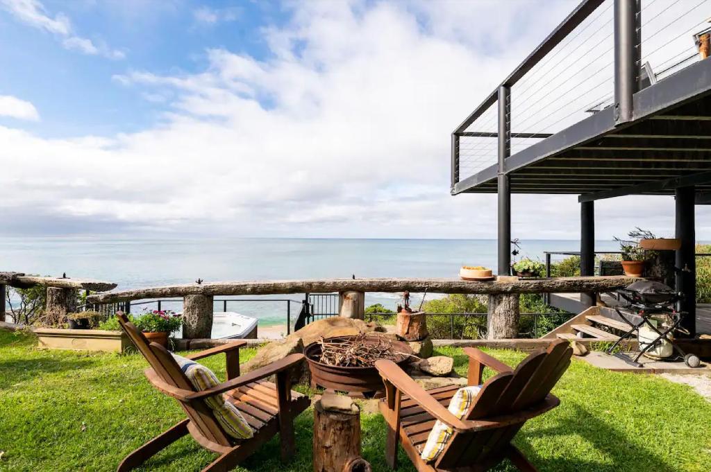 a couple of chairs sitting on the grass near the ocean at Y Vue - Beachside Apartment with Ocean Views in Wye River