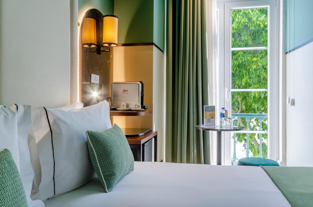 um quarto com uma cama branca e uma janela em Nicola Rossio Hotel em Lisboa