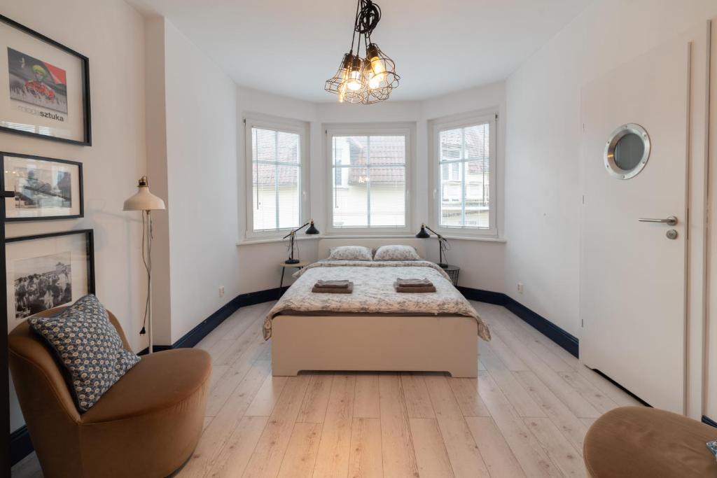 a bedroom with a bed and a chair and windows at Sopot, the very heart! in Sopot