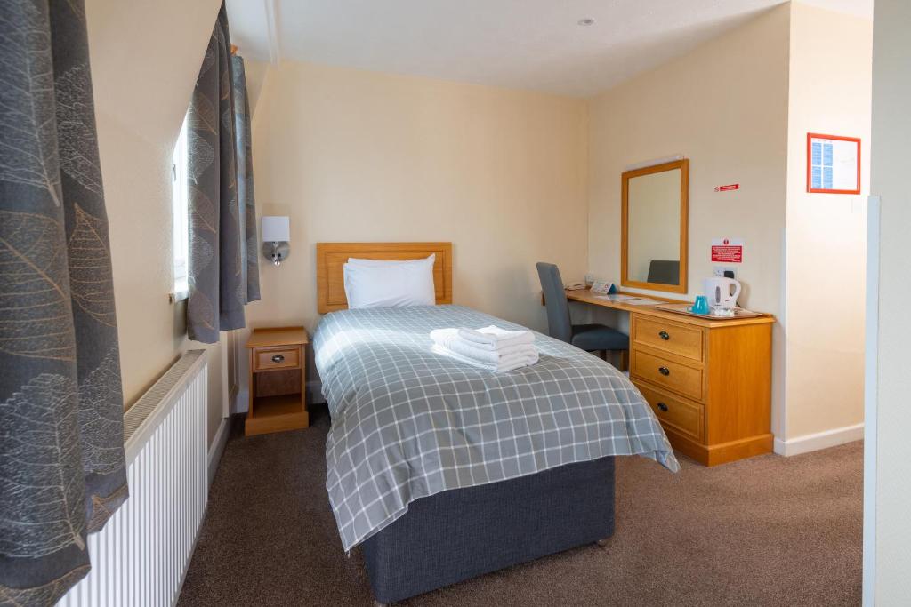 a bedroom with a bed and a desk and a mirror at The Crown Hotel in Weymouth