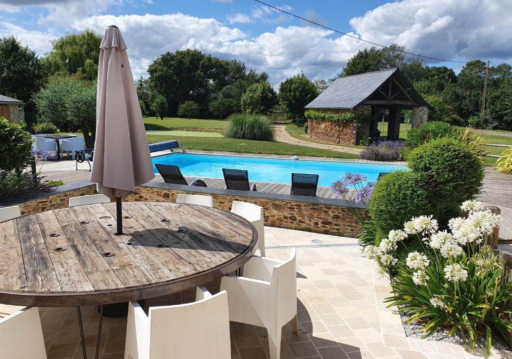 un tavolo con ombrellone accanto alla piscina di Maison de Campagne de charme avec piscine privée classée 3 étoiles a Champigné