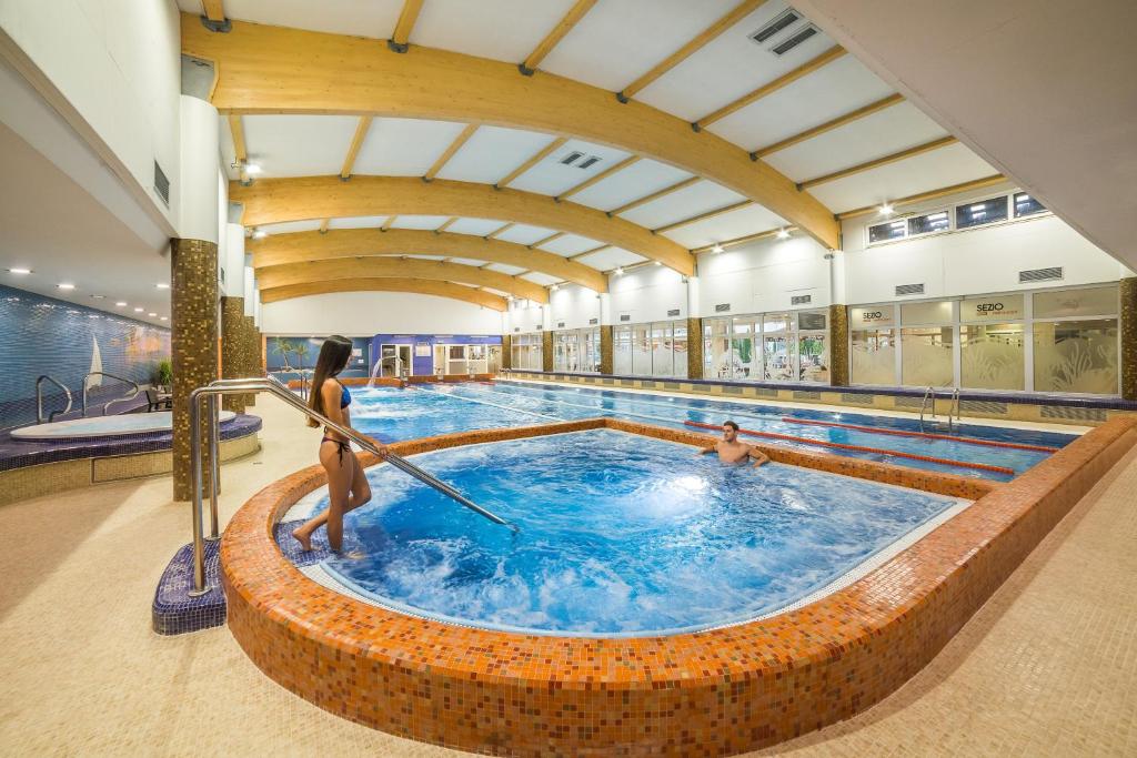 a large swimming pool with two people in it at Wellness Hotel Step in Prague