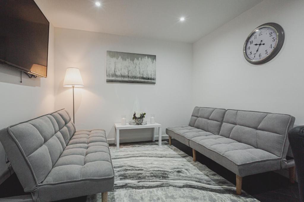 a living room with two couches and a clock on the wall at RST Luxury Aparthotel in Liverpool