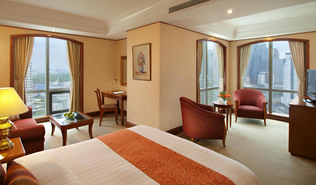 una camera d'albergo con letto, sedie e finestre di Richmonde Hotel Ortigas a Manila