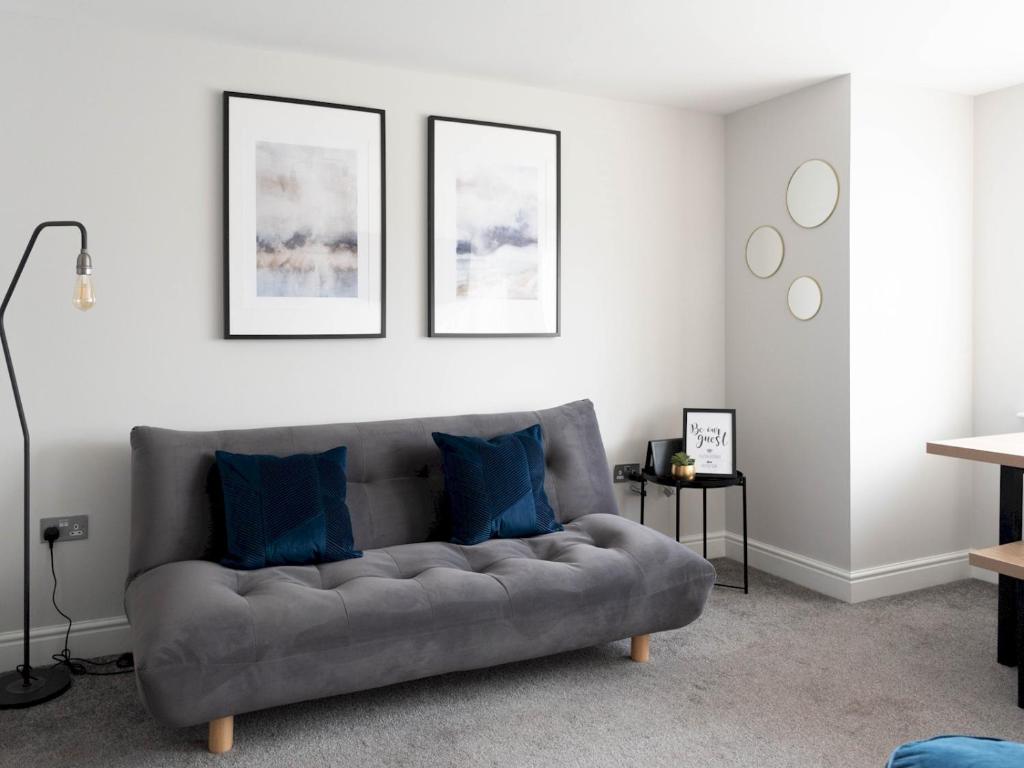 a living room with a gray couch with blue pillows at Pass the Keys Lovely, comfortable 2-bed Braehead - free parking in Renfrew
