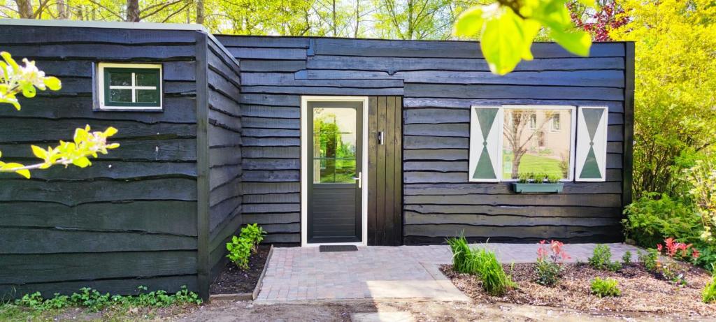 una pequeña casa negra con un revestimiento azul en De Vuurplaats en Drachten