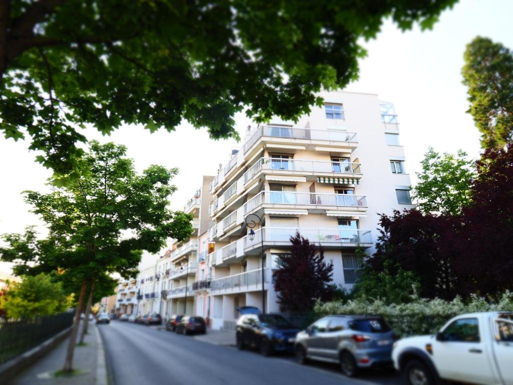 um edifício branco com carros estacionados ao lado de uma rua em ROCHAMBEAU - Moderne - Face aux Thermes - Parking - em Vichy