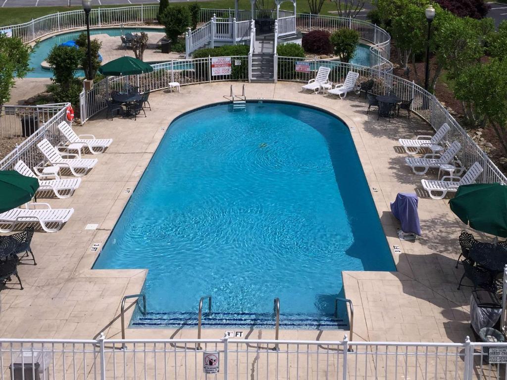 a large swimming pool with lounge chairs and tables at Clarion Inn Willow River in Sevierville