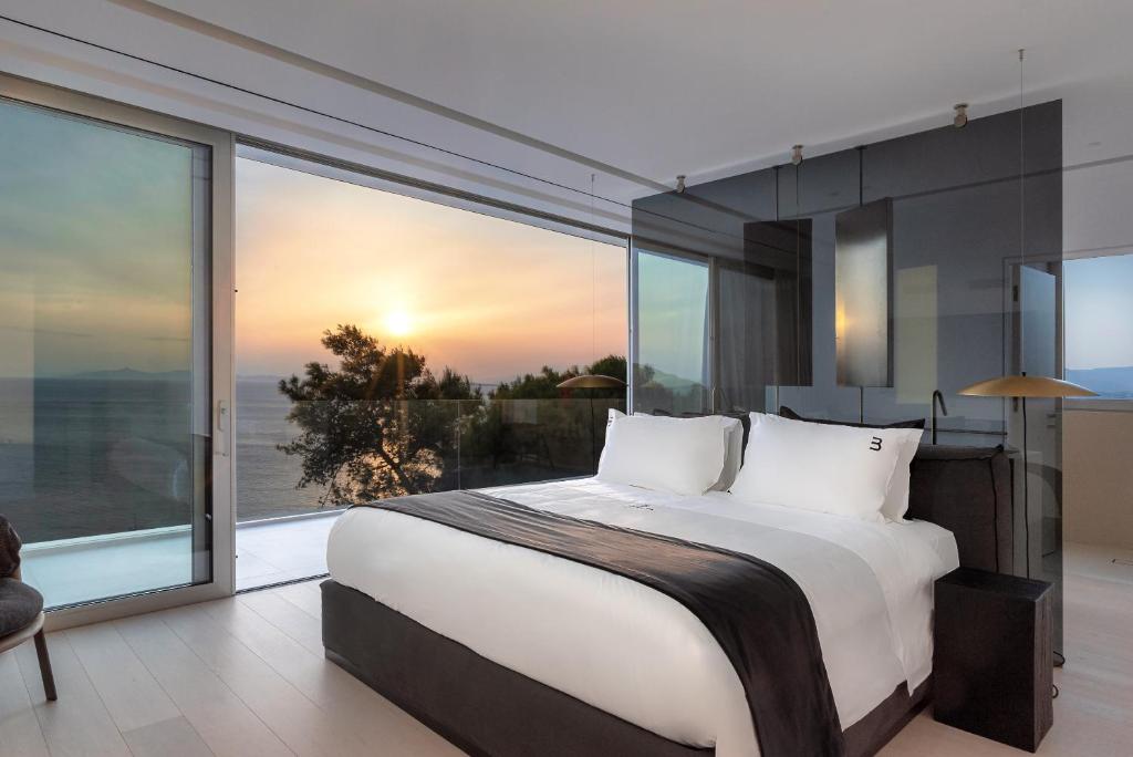 a bedroom with a large bed and a large window at Black Stone Villa in Sounio