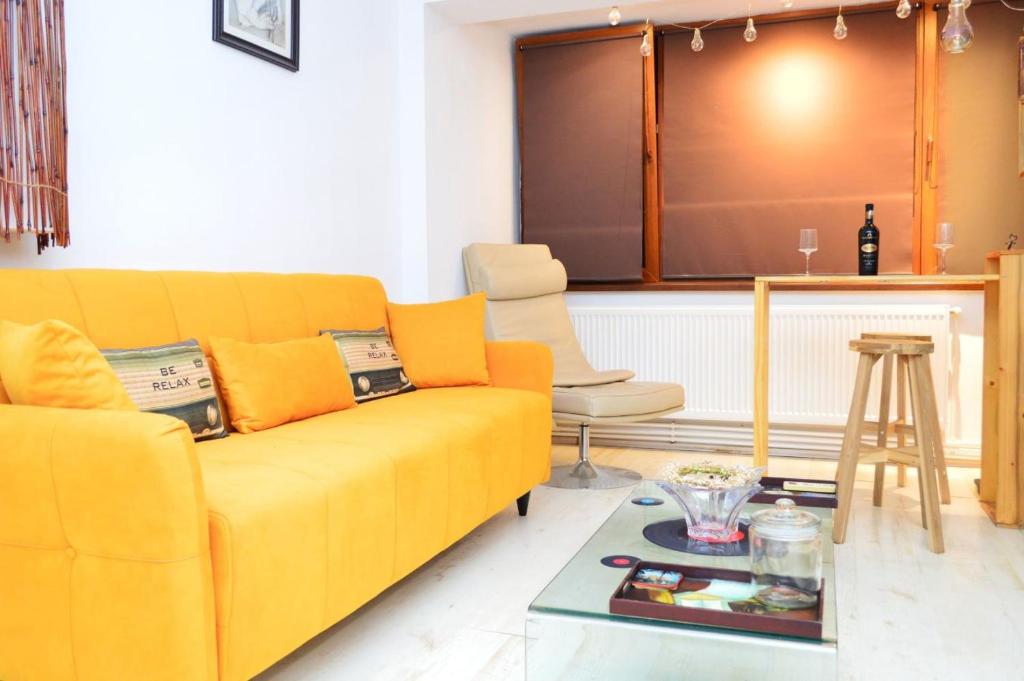 a living room with a yellow couch and a table at City Park Apartment in Constanţa