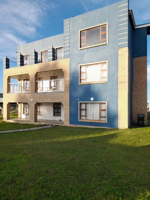 a blue house with a lawn in front of it at Sunset Guesthouse - Mthatha in Mthatha