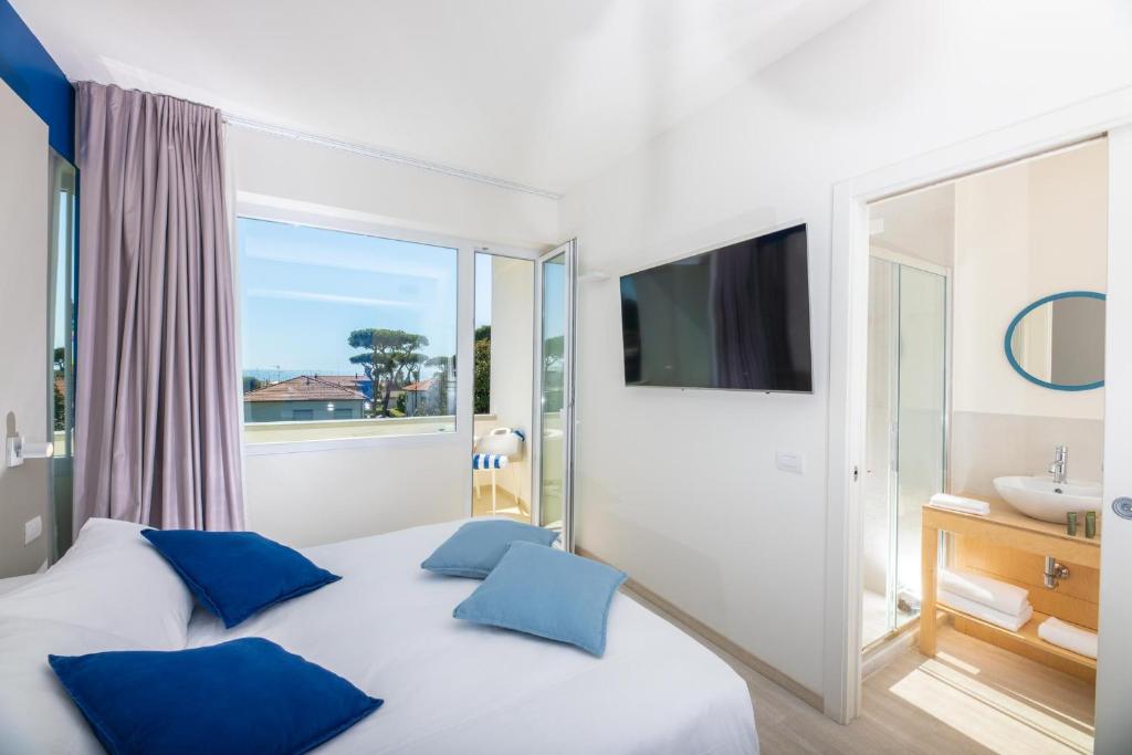 a bedroom with a bed with blue pillows and a window at Amarina Hotel in Marina di Pietrasanta