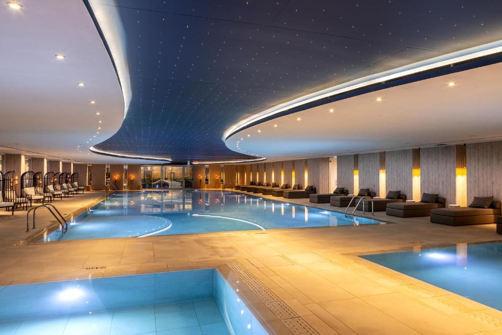 a pool in a hotel lobby with chairs and tables at Chrysomare Beach Hotel & Resort in Ayia Napa