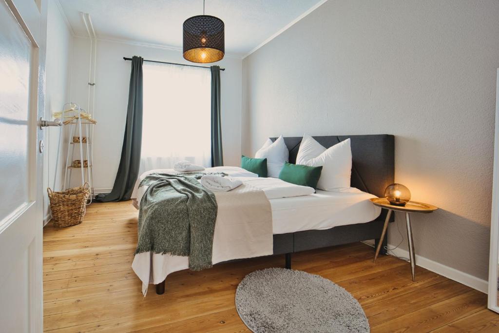 a bedroom with a bed with white and green pillows at HejU - Parking - Kitchen - Netflix - Kingsize Bett in Lübeck
