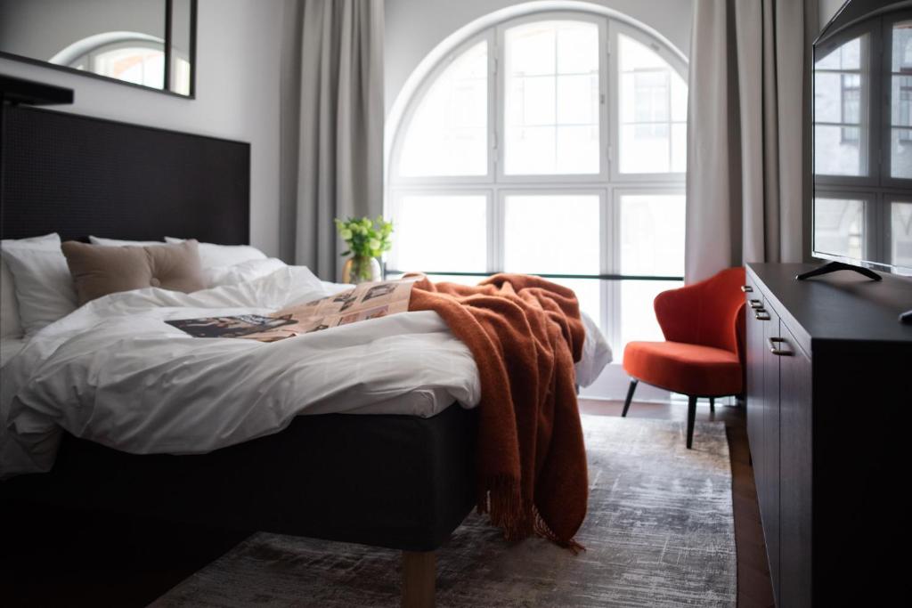 a bedroom with a bed and a red chair at Bob W Helsinki Katajanokka in Helsinki
