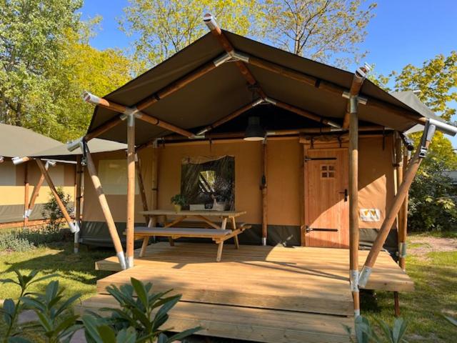 einen Pavillon mit einem Picknicktisch auf einer Holzterrasse in der Unterkunft Luxe Safaritent Medley 5 persoons op Camping Rijsterbos in Rijs