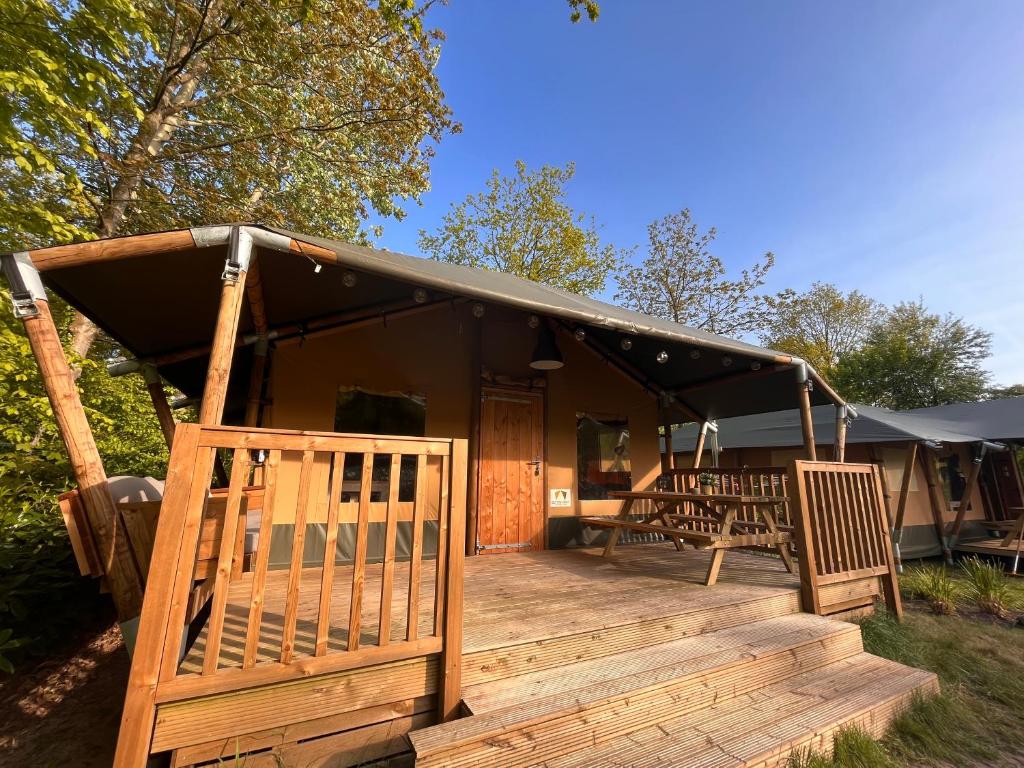 a cabin with a black roof and a wooden deck at Luxe Safaritent 6 persoons op Camping Rijsterbos in Rijs