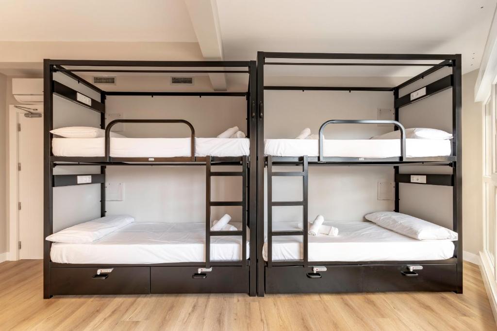 three bunk beds in a room with wooden floors at Uri Hostel Bilbao Rooms BBI00060 Self check in in Bilbao