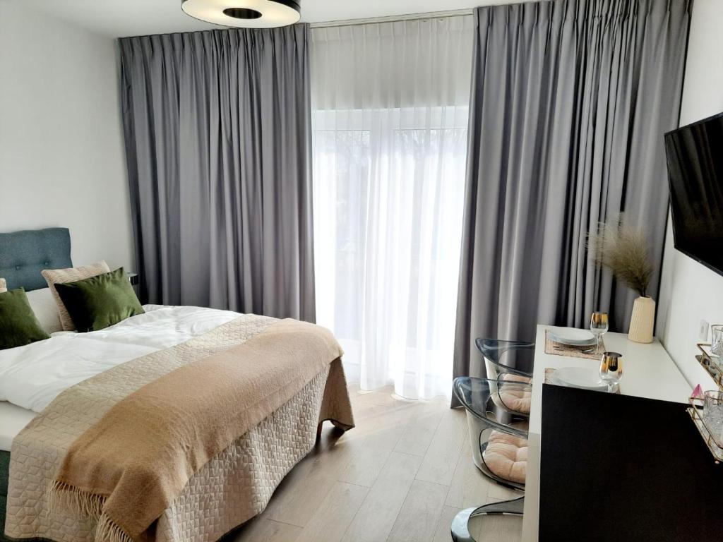 a bedroom with a bed and a large window at Apartamenty na Spokojnej in Kołobrzeg