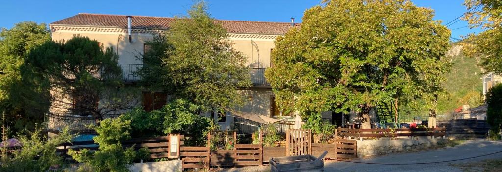 a building with a fence and trees in front of it at Essentiel Barret in Barret-sur-Meouge