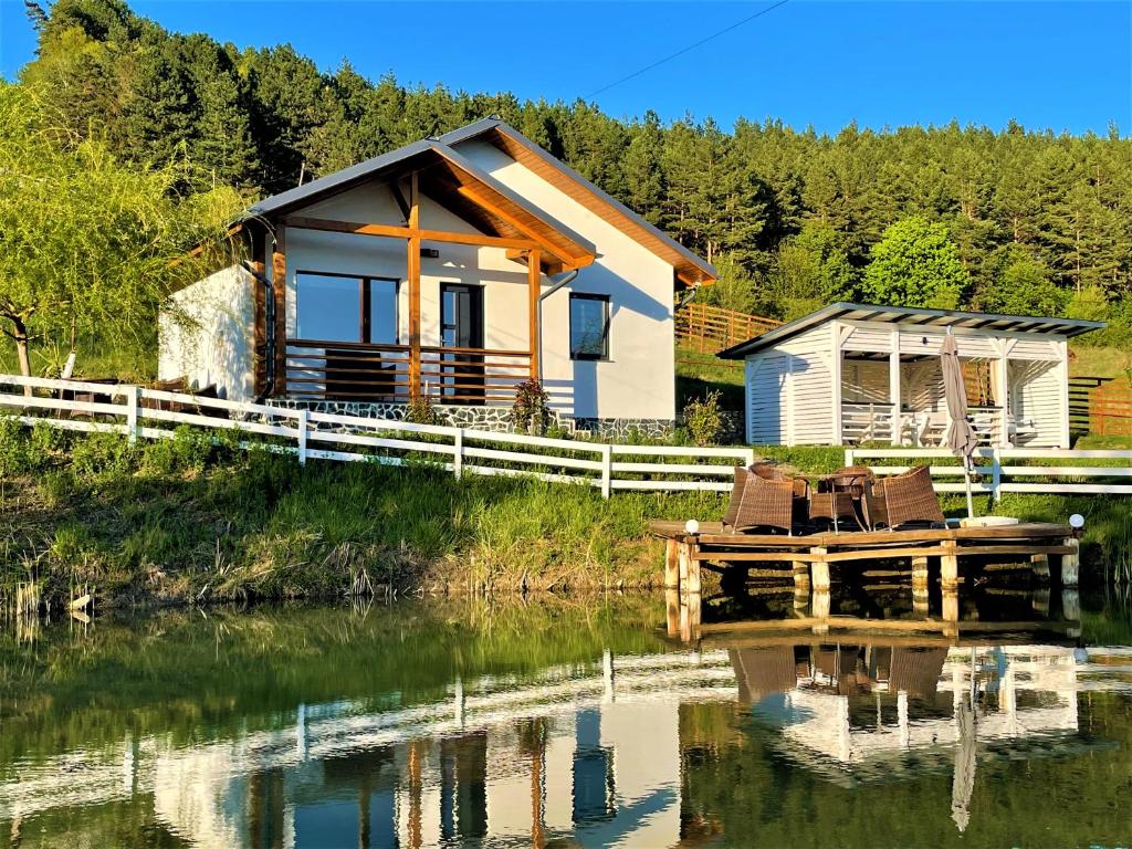 une maison sur l'eau avec des chaises devant elle dans l'établissement NOIA Caban, à Piatra Neamţ