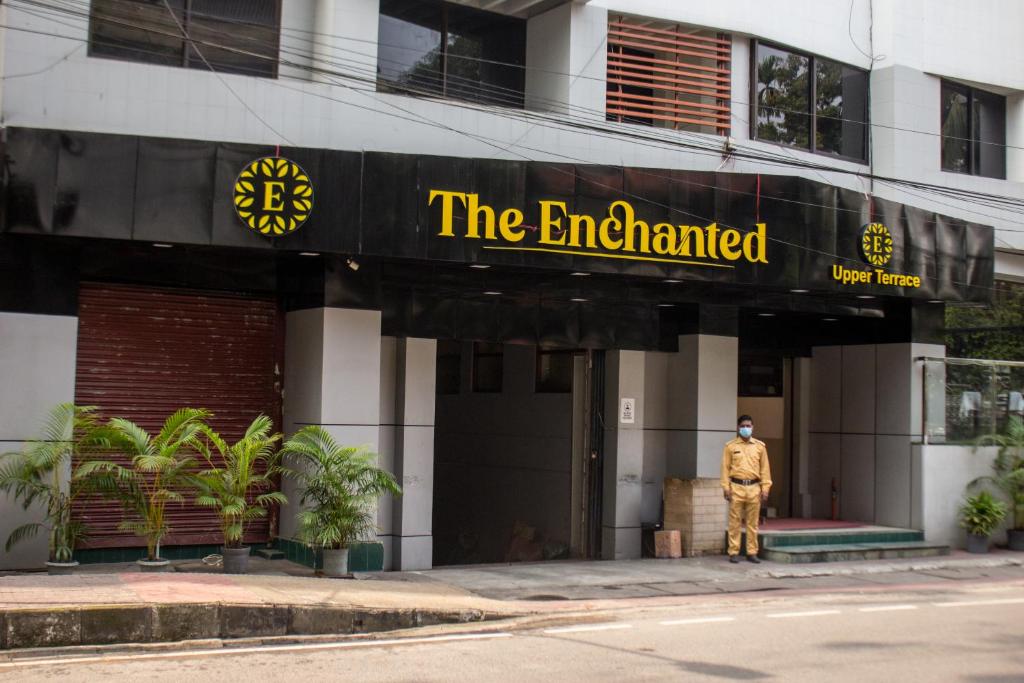 Un uomo in piedi di fronte a un edificio di Hotel The Enchanted a Dhaka