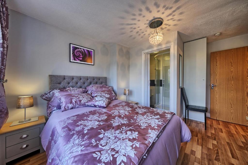 a bedroom with a purple bed and a chandelier at Upton Village Guest House in Birkenhead