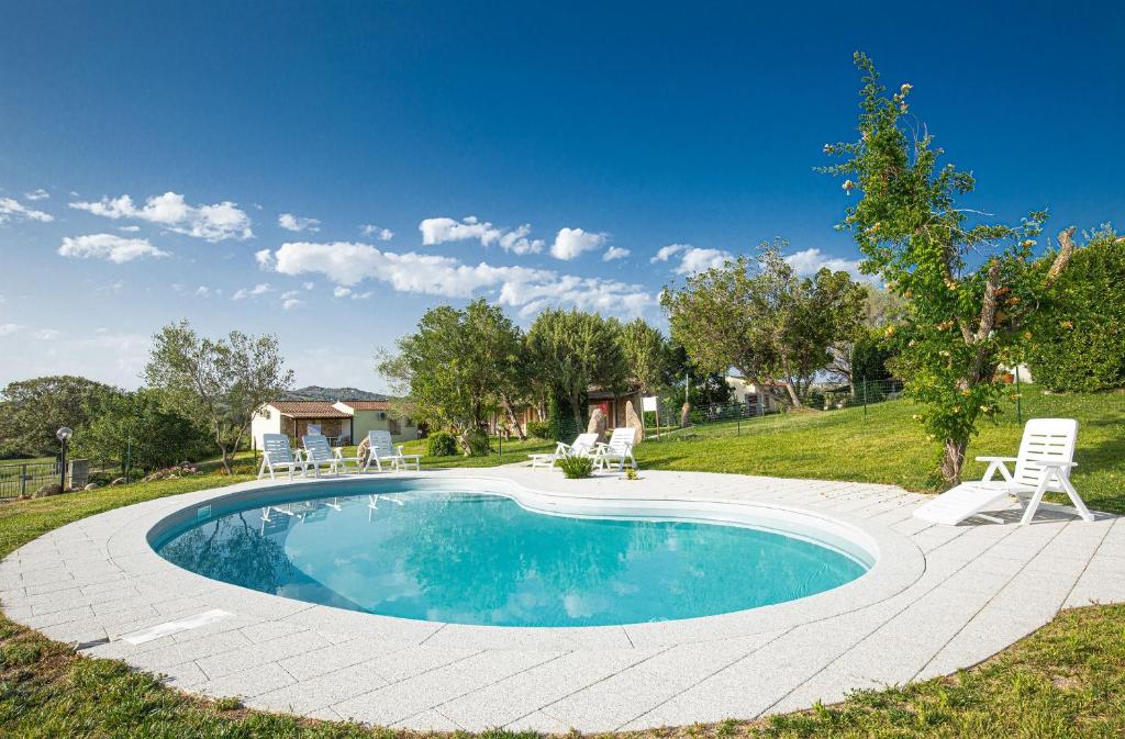 una piscina in un cortile con sedie intorno di Turismo Rurale CUDACCIOLU a Arzachena