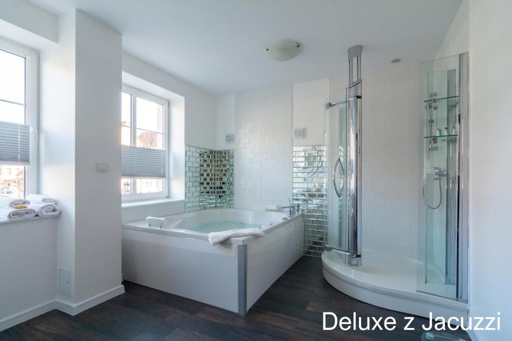 een witte badkamer met een bad en een douche bij Apartamenty nad Motławą in Gdańsk