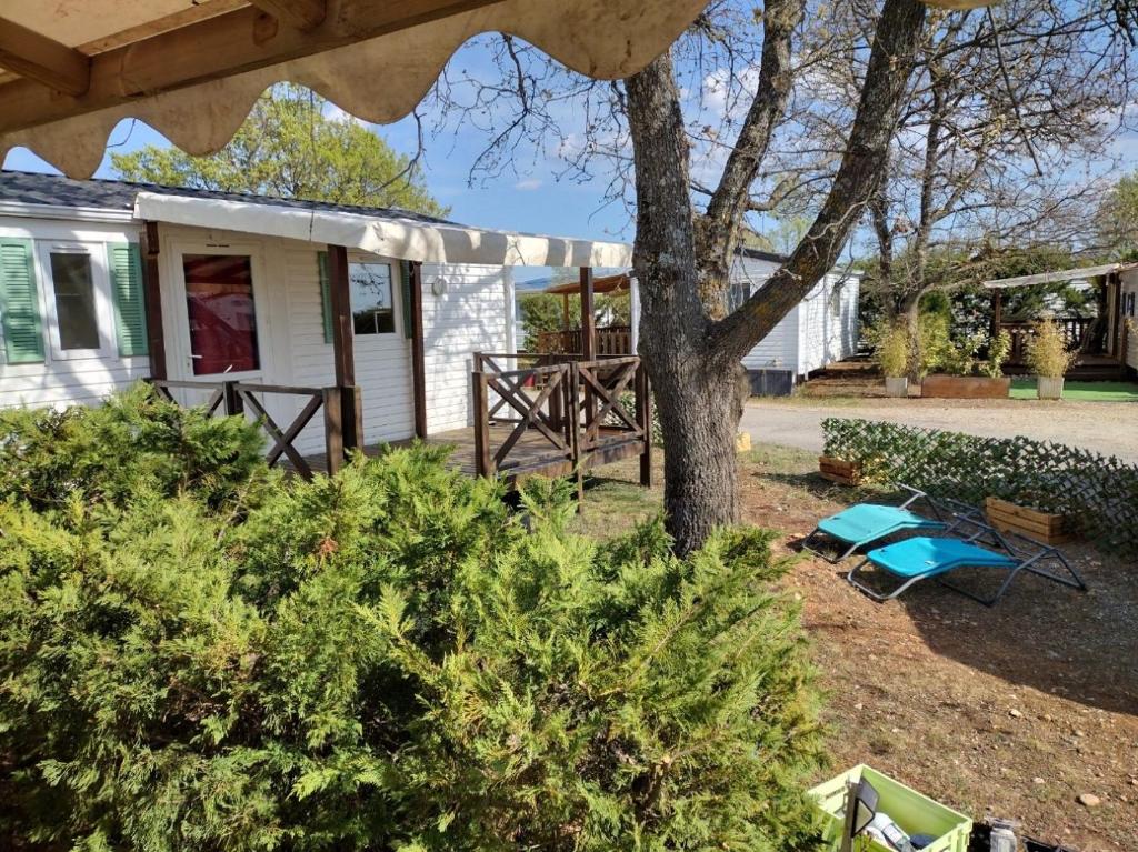 une maison avec un arbre dans la cour dans l'établissement MOBILHOME 4/5 P /GORGES DU VERDON / TOUT EQUIPE / / TOUT CONFORT / REFAIT A NEUF / LAC DE STE CROIX A PROXIMITE, à Sainte-Croix-de-Verdon