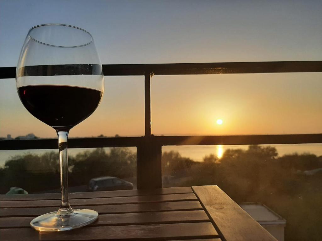 a glass of wine sitting on a table with the sunset at Vistas del Guadiana in Ayamonte