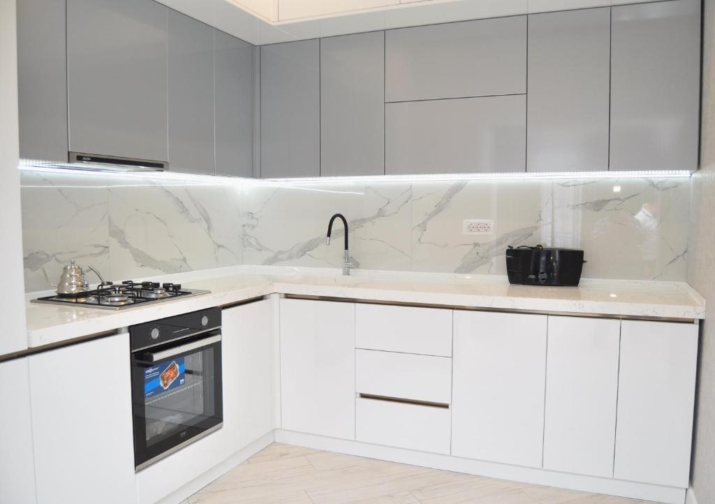 a white kitchen with white cabinets and a sink at Seaside Luxury Apartment in Sumqayıt