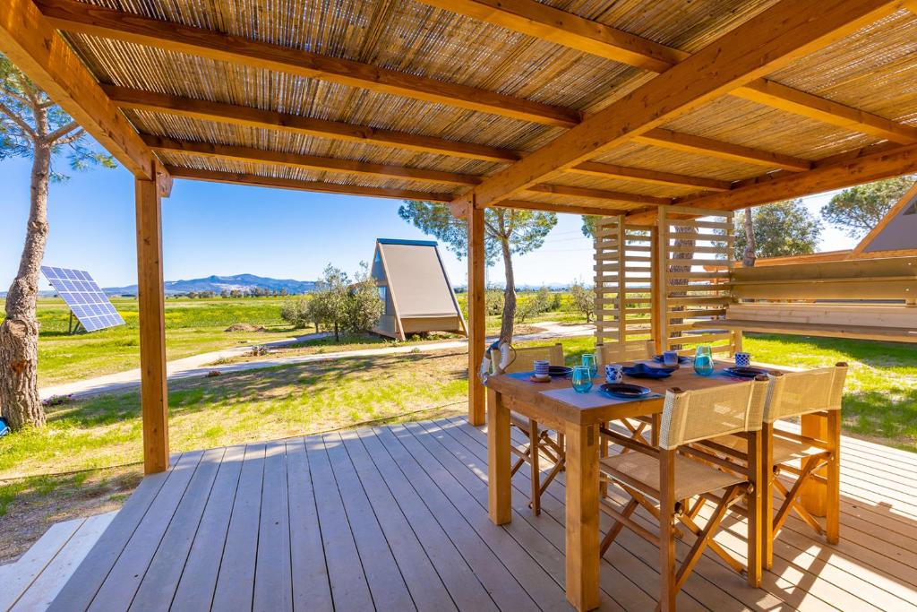 a wooden patio with a table and chairs on a deck at Glamping Gli Etruschi in Piombino